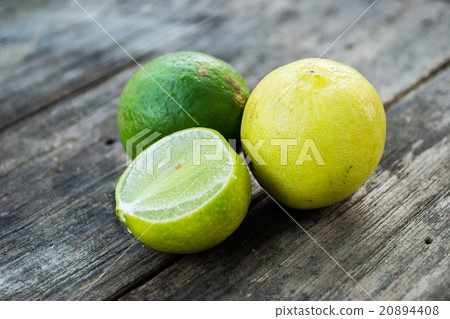 Two limes and sliced one on wooden table Two limes and sliced one on wooden table 20894408