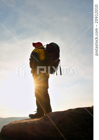 Silhouette of tourist with cap, backpack on rock 20912010