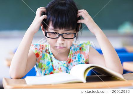 Depressed little girl studing in the classroom 20912923