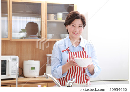 一個60多歲的女人站在廚房裡 20954660