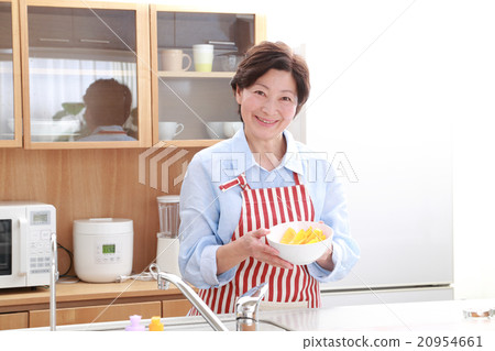 A woman in her 60's who stands in the kitchen A woman in her 60's who stands in the kitchen 20954661