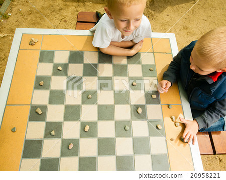 Children playing draughts or checkers board game outdoor Children playing draughts or checkers board game outdoor 20958221
