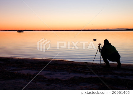 Nature photographer at tripod takes photo on beach Nature photographer at tripod takes photo on beach 20961405