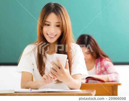 young female student using smart phone in classroom young female student using smart phone in classroom 20966098