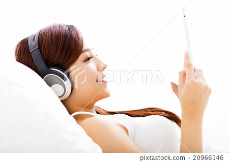 young Woman with headphones and tablet on the bed young Woman with headphones and tablet on the bed 20966146