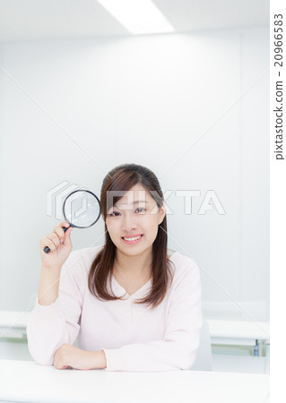 Woman holding a magnifying glass Looking at the camera 20966583