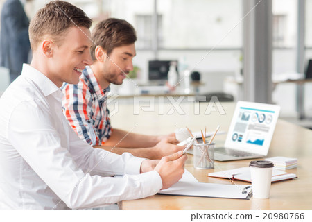 Cheerful men holding their cell phones Cheerful men holding their cell phones 20980766