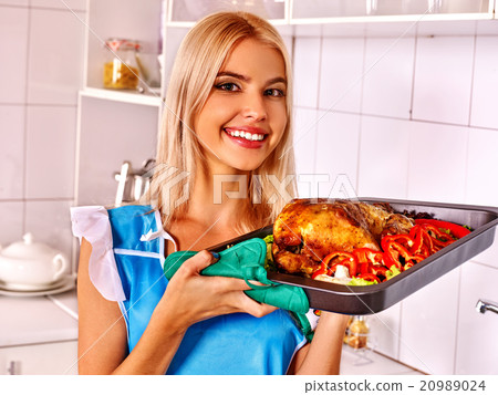 Woman cooking chicken at kitchen. 20989024