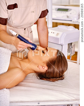 Young woman receiving electric facial massage. 20989165