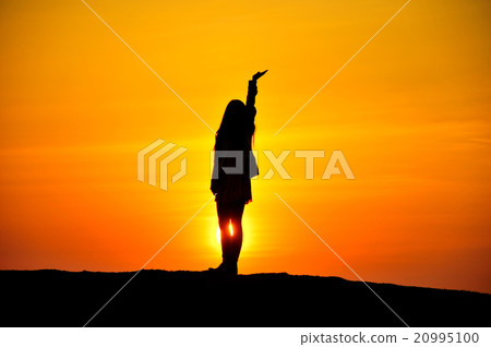 A woman's silhouette floating in the setting sun A woman's silhouette floating in the setting sun 20995100
