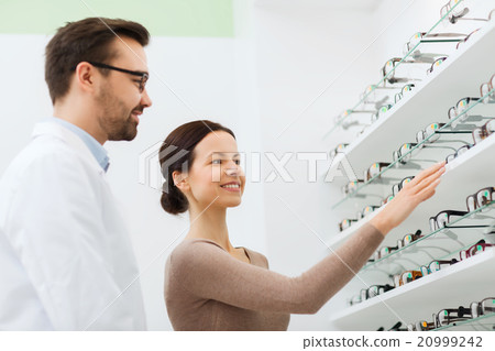 woman showing glasses to optician at optics store 20999242