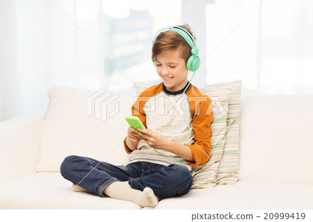 happy boy with smartphone and headphones at home 20999419