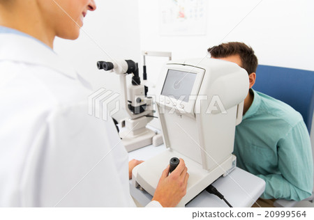 optician with autorefractor and patient at clinic 20999564