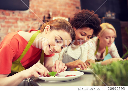 happy women cooking and decorating dishes 20999593