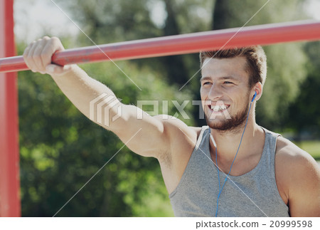 happy young man with earphones and horizontal bar 20999598
