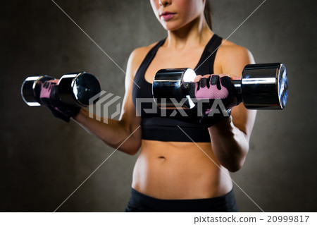close up of woman flexing arms with dumbbells 20999817