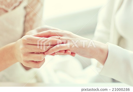 close up of lesbian couple hands with wedding ring 21000286