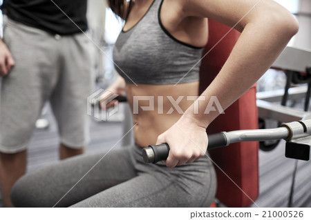 close up of woman flexing muscles on gym machine 21000526
