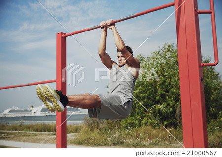 young man exercising on horizontal bar outdoors young man exercising on horizontal bar outdoors 21000567
