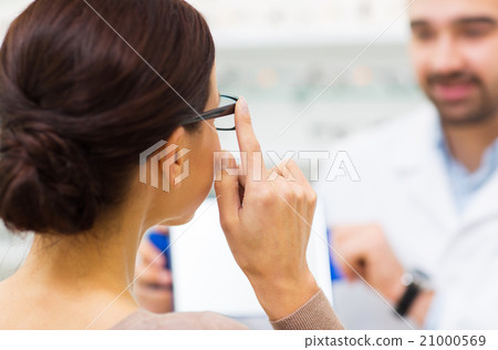 close up of woman choosing glasses at optics store close up of woman choosing glasses at optics store 21000569