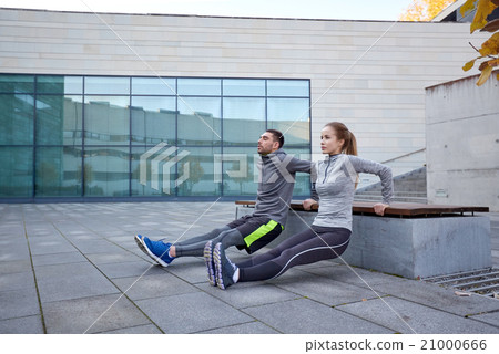 couple doing triceps dip exercise outdoors 21000666