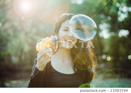 Beautiful young woman playing bubble in sunlight. 21003594