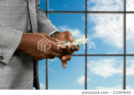 Businessman counts money near window. 21004640
