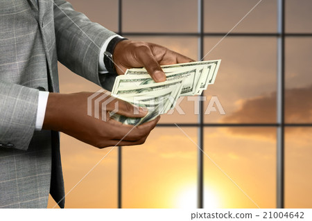 Black office employee counts income. 21004642