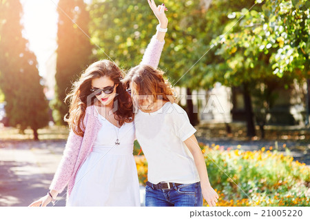 Two young happy women walking in the summer city Two young happy women walking in the summer city 21005220