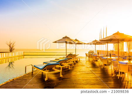 Umbrella and chair around swimming pool 21009836