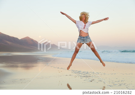 Young beautiful woman jumping in the beach. 21016282