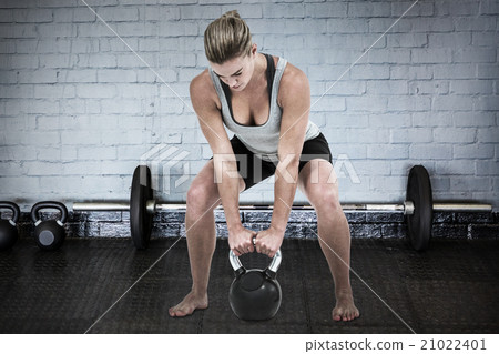 Composite image of serious muscular woman lifting kettlebell Composite image of serious muscular woman lifting kettlebell 21022401