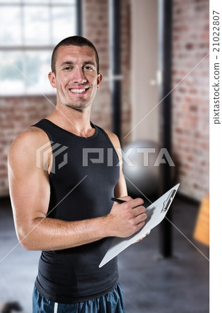 Composite image of smiling sports coach writing on clipboard 21022807