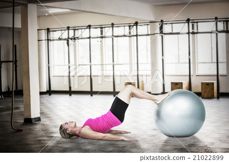 Composite image of side view of woman exercising with ball 21022899