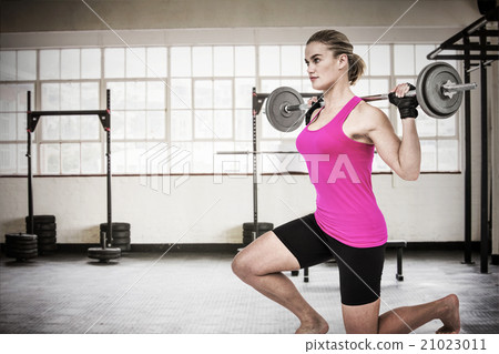 Composite image of sporty female bodybuilder lifting barebell Composite image of sporty female bodybuilder lifting barebell 21023011