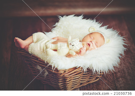 Cute newborn baby in bear hat sleeps in basket with toy teddy be Cute newborn baby in bear hat sleeps in basket with toy teddy be 21030736