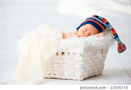 Cute newborn baby in blue knit cap sleeping in basket Cute newborn baby in blue knit cap sleeping in basket 21030738