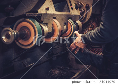 Shoemaker performs shoes with grinder machine. 21044070