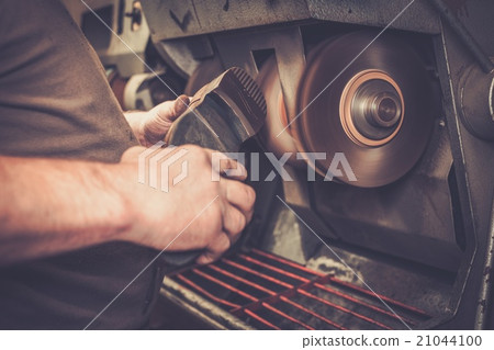 Shoemaker repairs shoes with grinder machine. Shoemaker repairs shoes with grinder machine. 21044100