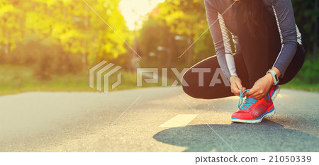 Stock Photo: Female runner tying her shoes preparing for a jog