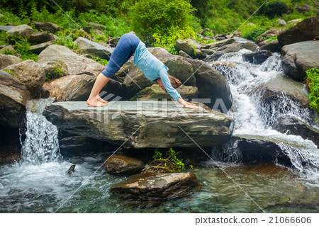 Woman doing yoga oudoors at tropical waterfall 21066606
