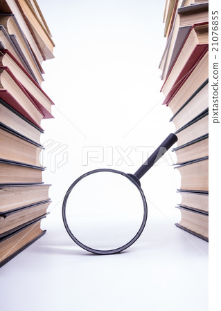 Stack of books with magnifying glass. Search 21076855