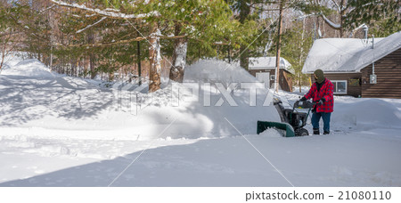 A man operates a snow thrower. Canadian winter. A man operates a snow thrower. Canadian winter. 21080110