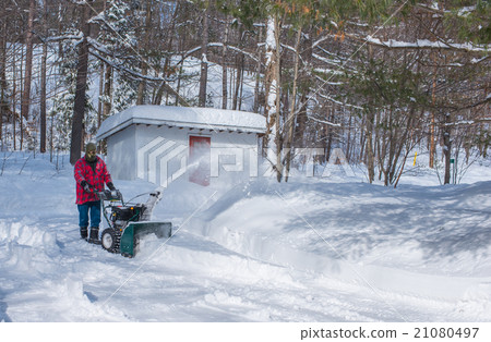 A man operates a snow thrower on a winter day. 21080497