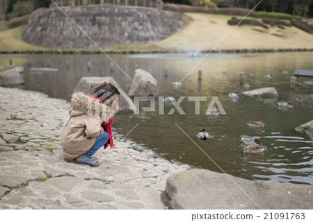 A girl playing at the side of a pond 21091763
