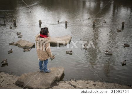 A girl playing at the side of a pond 21091764