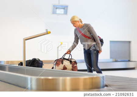 Female traveller collecting luggage at airport. 21092631