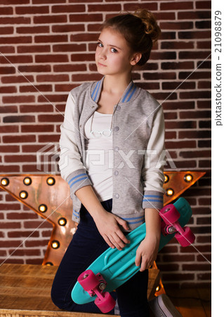Pretty teen girl with skateboard over brick wall 21098879