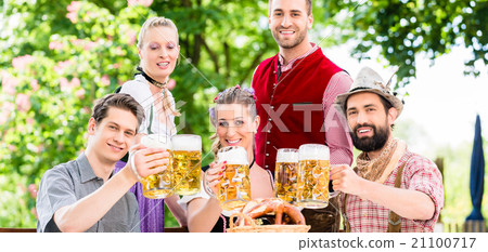 Friends in Bavarian beer garden drinking in summer Friends in Bavarian beer garden drinking in summer 21100717