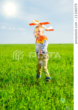 Happy boy playing with toy airplane against blue 21106079